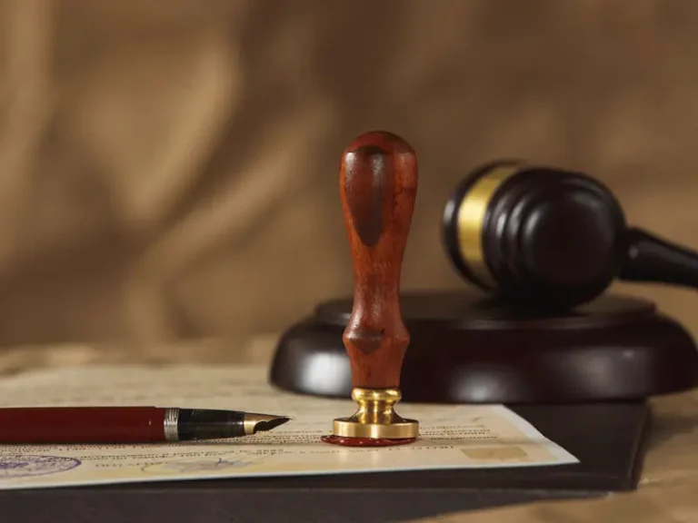 A wooden seal stamp, gavel, and fountain pen on a document, with a soft-focus background.