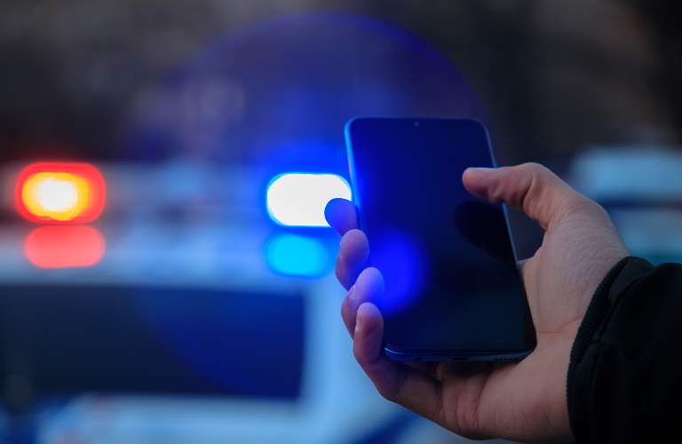 man holding smartphone against police car