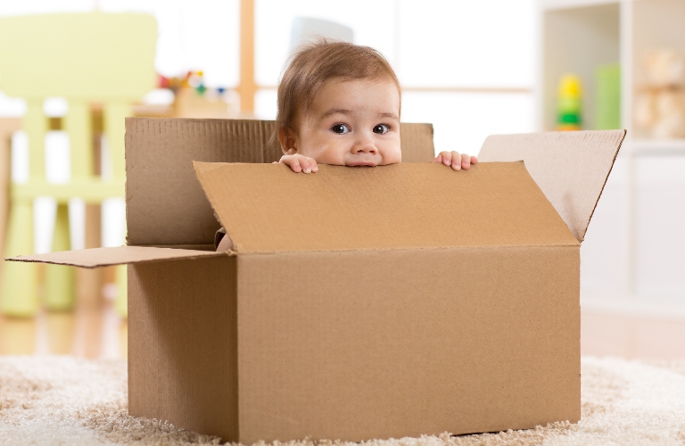 A cute baby boy is sitting in a box