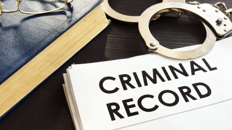 Criminal record and handcuffs on a desk