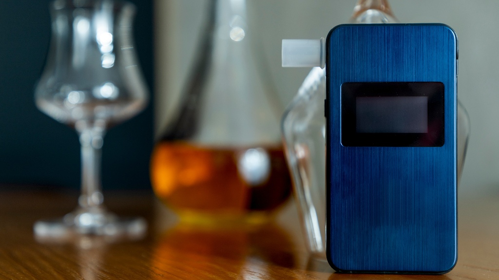 Alcohol breathalyzer next to a glass of whiskey