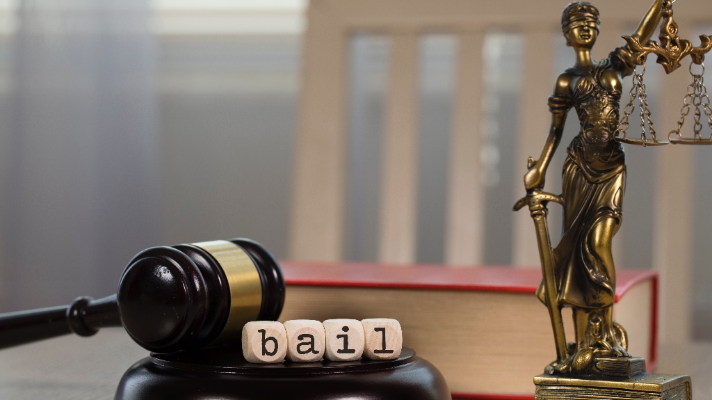 Word Bail composed of wooden dices, judge's gavel, statue of Lady Justice