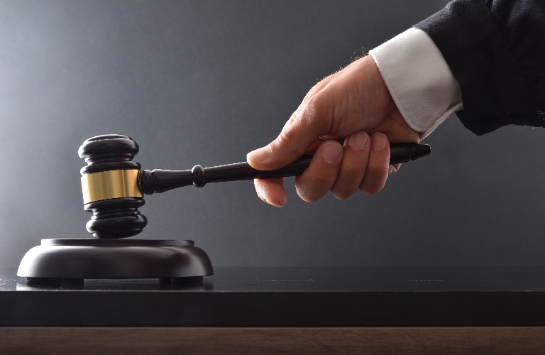 Hand striking on wooden base with judge's gavel