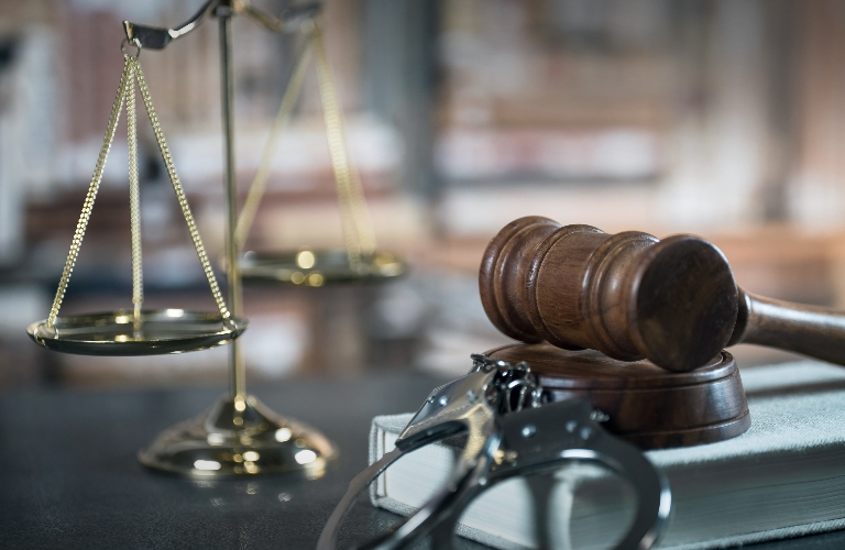 Handcuffs and gavel on dark rustic table