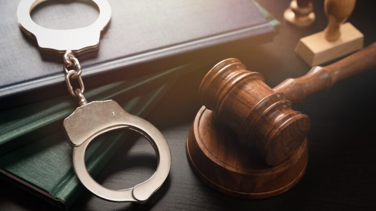 Metal handcuffs near judge gavel