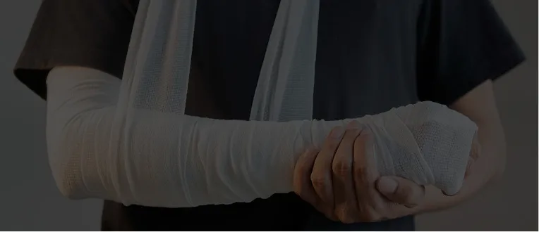 Person wearing a black shirt with a fully bandaged arm supported by a sling.