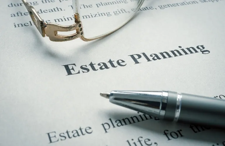 Close-up of a document titled "Estate Planning" with a pen and eyeglasses resting on the paper.