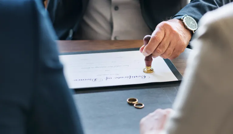 Close-up of a person sealing a document with a wax stamp on a wooden table.