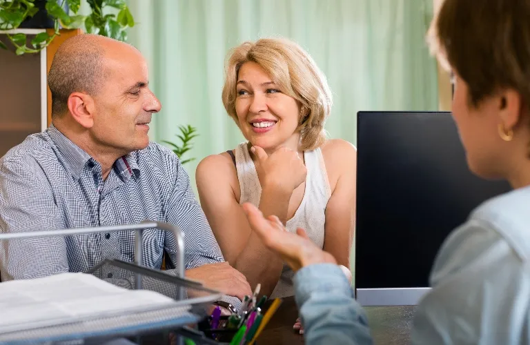 Middle-aged couple attentively listening to a professional during a consultation at an office.