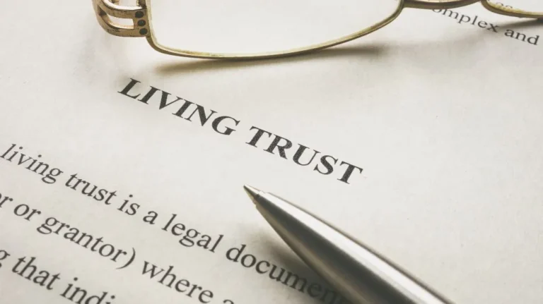 Close-up of a living trust legal document with a silver pen and reading glasses.