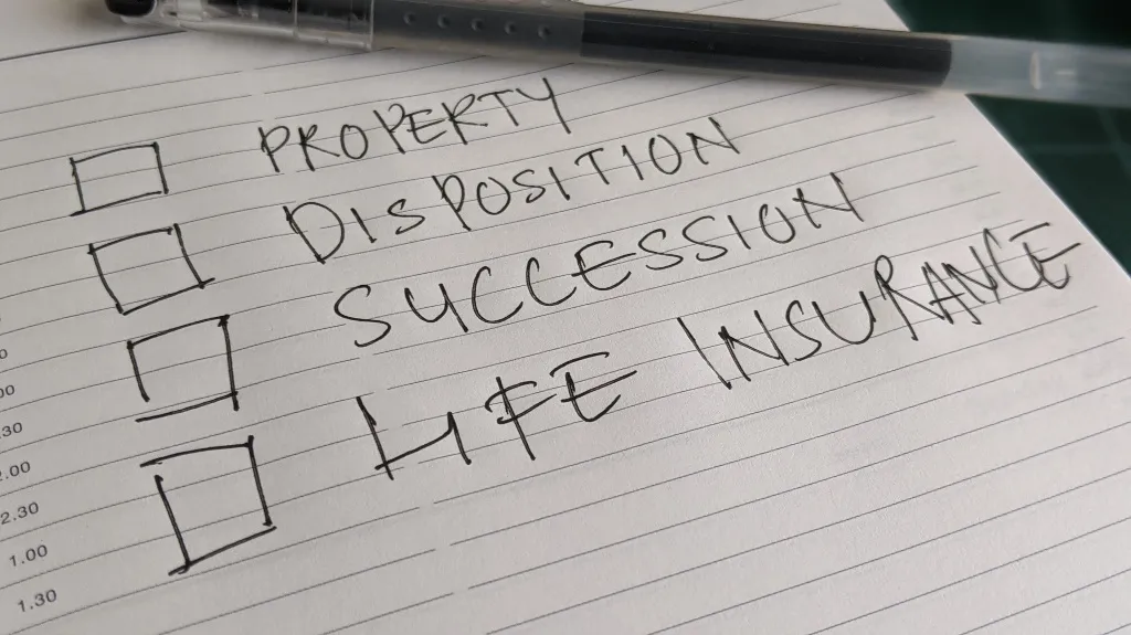 Close-up of a lined notebook page with handwritten checklist including property disposition, succession, and life insurance.
