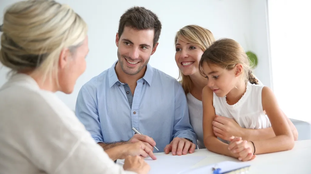 Family of three, including a man, woman, and girl, consulting with a professional woman.